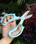 Pro Grade Garden Pruning Scissors With Comfort Grip Handle Set Razor Sharp SK5 Stainless Steel Floral Scissors in hand among flowers