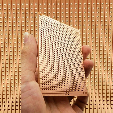 Hand holding 73x100mm copper strip board, Ten Pack 73 By 100 Millimeter Copper Strip Board With 957 Holes Perfboard Kit