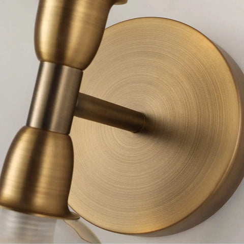 Close-up of a gold fixture on the Rock This Mini Two Light Gold Bathroom Vanity Wall Sconce With Clear Glass Shades