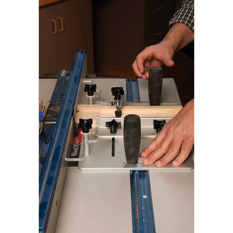 Hands using Router Table Coping Sled Kit With Sacrificial Backing Board and toggle clamps for precise cuts in wood.