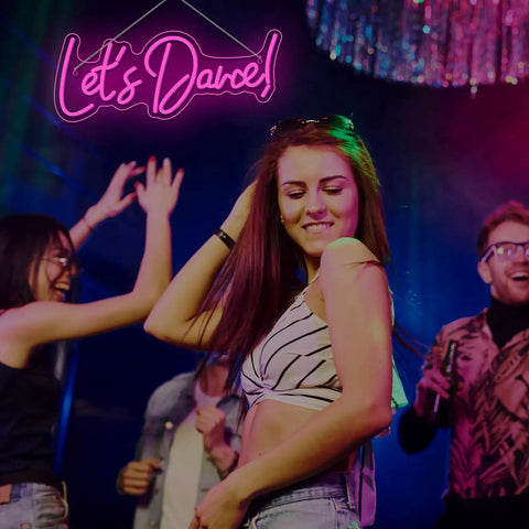 Young adults dancing under Lets Dance Neon Sign Pink LED Word Light for Weddings and Parties, vibrant party atmosphere.