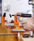Heavy Duty 6 Inch Steel Bar Clamp for Woodworking and DIY Projects, Orange, Sure Grip Construction, Reaches Up To 3 Inches From Edge To Screw Center, Maximum Opening 6 Inches, Built For Hard Use By Hobbyists And Pros. Orange steel bar clamp holding wood in workshop