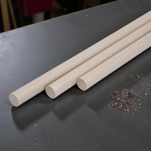 Beige PEEK Plastic Round Rod One Quarter Inch by 24 Inches Three Pack for engineering projects and fabrication on a workshop table.