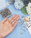 Hand holding items from All In One Jewelry Making Kit With 304 Stainless Steel Findings 200 Fold Over Crimp Cord Ends 200 Jump Rings 50 Lobster Clasps For Earrings Bracelets And Necklaces DIY Craft Making, with box.