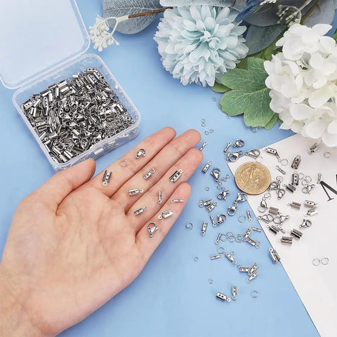 Hand holding items from All In One Jewelry Making Kit With 304 Stainless Steel Findings 200 Fold Over Crimp Cord Ends 200 Jump Rings 50 Lobster Clasps For Earrings Bracelets And Necklaces DIY Craft Making, with box.