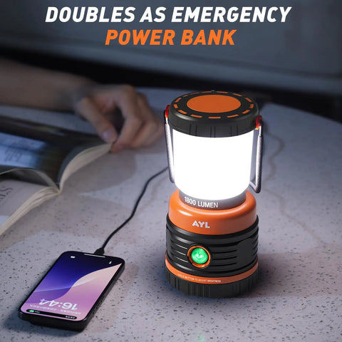 Beast Bright Rechargeable LED Camping Lantern 1800 Lumens illuminating a table, charging a phone, with a book nearby.