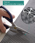 Person cutting a gray Commercial Drainage Mat 3x10 Ft 0.22 Inch Thick Grippy Non Slip PVC Floor Rug with scissors, showing easy trimming.