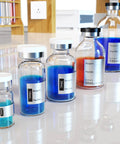 Front view of borosilicate glass reagent vials with white caps and metal crimp seals, blue liquids in varied sizes.
