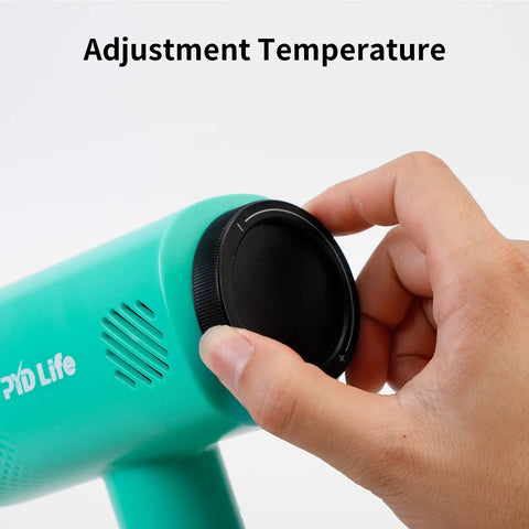 Hand adjusting temperature knob on Mint Green Heat Blower Gun With Foldable Handle For Sublimation Blanks And Shrink Wrap Film, 110V 1300W Hot Air Gun With Adjustable Dual Gear Speeds For Precise Shrink Wrapping.