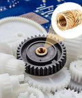 Close-up of 100 Pcs M3 Heat Set Threaded Inserts For 3D Printing Brass Knurled Twill Nuts, installed in a black plastic gear.