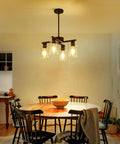 Sleek Modern Black Four Light Farmhouse Chandelier Featuring Crisp Cylindrical Glass Shades Fully Adjustable Height above dining table.