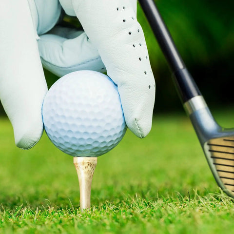 Gloved hand placing golf ball on 500 Pcs Bamboo Golf Tees 3-1/4 Inches Long Wooden Tees For Golf Practice On The Course Natural Color