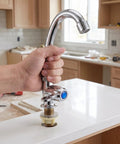 Hand installing a Vertical Kitchen Sink Faucet, Plastic Small Countertop Tap with 2cm Base on white countertop.