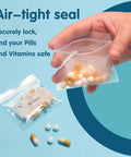 Hand holding 125 Packs 6 Mil Pill Bags BPA Free Waterproof Zip Lock Pouches 3 x 2.75 Inch with pills inside, blue background.