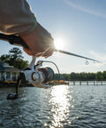 Angler casting with Max Pro Spinning Rod And Reel Combo 6 Foot 10 Inch, Size 2500 Reel, by a sunny lakeside