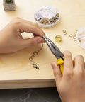 Hands using pliers on necklace with Over 1000 Open Jump Rings Kit With 40Pcs 12Mm Lobster Clasps And Jump Ring Opener in gold finish
