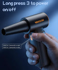 Hand holding a Powerful Cordless Air Duster with Brushless Motor 260000 RPM, shown from the side with power button visible.