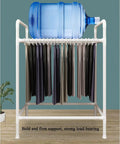 Space Saving Trouser Rack With 15 Heavy Duty Pants Clips And Smooth Wheels, holding trousers and supporting a water bottle.