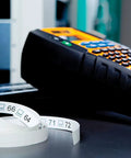 RhinoPRO 5200 Heavy Duty Label Maker With Carry Case for Job Sites with printed vinyl labels on dark surface.