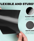 Hands holding a flexible black sheet showing glossy and matte sides, part of Pack Of 25 Non Adhesive Flexible Magnetic Sheets For Arts And Crafts.