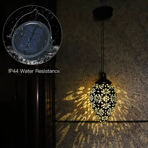 Olive Shaped Hanging Solar Lantern With LED Garden Lights, Weatherproof Metal Lamp casting patterns on a wall, night view.