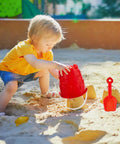 Child playing in sand with Six Pack 7 Inch Beach Sand Buckets And Shovels Set With Colorful Castle Molds For Sandbox Or Pool Party Favors