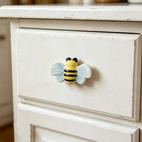 Hella Cute Yellow Honey Bee Ceramic Drawer Knobs And Cabinet Pulls attached to a white drawer front, adds charm to kids furniture.