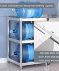 Top Grade Rust Proof Stainless Steel Shelving System With Four Tier Heavy Duty Storage Rack storing large blue water bottles in kitchen.