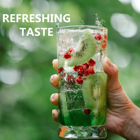Hand holding a glass of green fruit-infused water with kiwi and berries, showcasing refreshment.