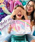 Smiling child holding unicorn-themed gift with text 'Make the Perfect Gift' beside adult, surrounded by colorful balloons and decorations.