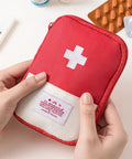 Red first aid pouch with white cross being held, resembling Must Have Emergency First Aid Bag Grab And Go Medical Kit.