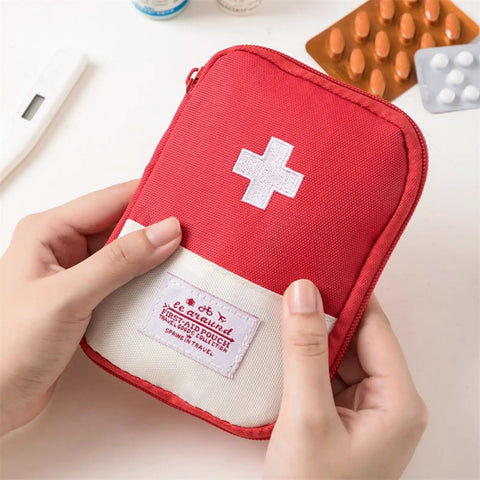 Red first aid pouch with white cross being held, resembling Must Have Emergency First Aid Bag Grab And Go Medical Kit.