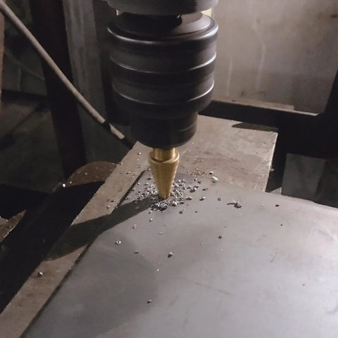 Step Drill Bit Set Unibit 5 Piece HSS Titanium Coated drilling into metal sheet, visible drilling process close-up view