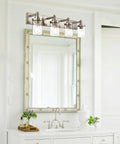 Four Light Vanity Light In Brushed Nickel With Clear Glass Shades mounted above a bathroom mirror