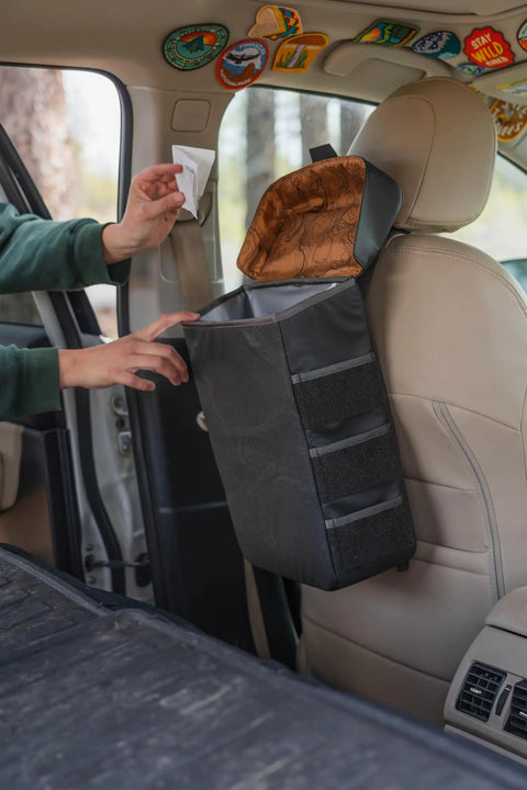 Trasher Vehicle Trash Can For Cars And Trucks, Rugged Modular Utility Bag installed behind car seat with magnetic lid open.