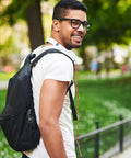 Man with backpack featuring three pack survival whistles keychain with directional indicator for outdoor emergency use.