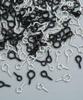 Must Have 300Pcs Small Screw Eye Pins For Jewelry Making And DIY Crafts in silver and black, three sizes scattered on a surface