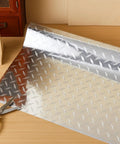 Diamond Plate Silver Vinyl Wrap Peel And Stick Contact Paper for Cabinets And Surfaces on table next to scissors