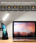 LED Desk Lamp With Wireless Charger 3 in 1 Fast Charging Station Touch Control Desk Lamp With Clock Alarm 3 Lighting Modes And Stepless Dimming For Home Office Eye Caring Black next to laptop and phone.