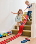Kids playing with 16 Ft Flexible Race Track With Suction Cups for Diecast 1 64th Cars on stairs, red track toy for indoor fun