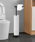 Stand-alone toilet paper holder with multiple rolls, matte black metallic finish, next to a toilet in modern bathroom setting.