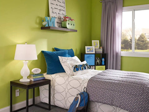 Bright bedroom with green walls, modern decor, and bed next to a lamp on a side table. Window view and natural light.