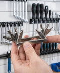 Hand holding Eight In One Bike Multitool with hex keys 2mm to 6mm, Torx T25, Phillips screwdriver in a workshop setting.