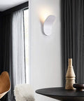 Modern Led Wall Sconce Featuring Smooth Iron Body And Soft Acrylic Diffuser, illuminating a stylish living room corner.