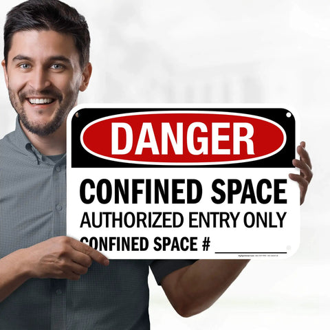 Man holding a warning sign stating 'Danger Confined Space Authorized Entry Only' for safety in restricted areas.