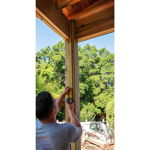 Person using Pro Grade 1-3/16 Inch By 35 Foot Tape Measure With Anti Pinch Retract outdoors on a wooden post.