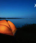Glowing tent by a serene lake at night under a crescent moon, ideal for camping. Compact Two Cell AA LED Flashlight nearby.