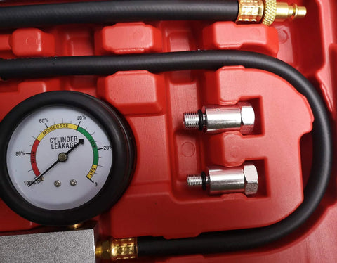 Automotive cylinder leak-down tester kit (front view) with dual gauge, red case, black hoses, metal adapters.