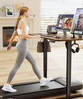 Woman using treadmill desk with dual monitors and laptops in home office setting with modern decor.