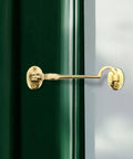 Durable Brass Storage Hook With Swivel Eye Latch For Cabinets And Doors installed on green door and white frame